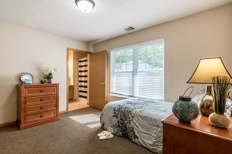 A cozy bedroom with a bed, dresser, and window providing natural light.
