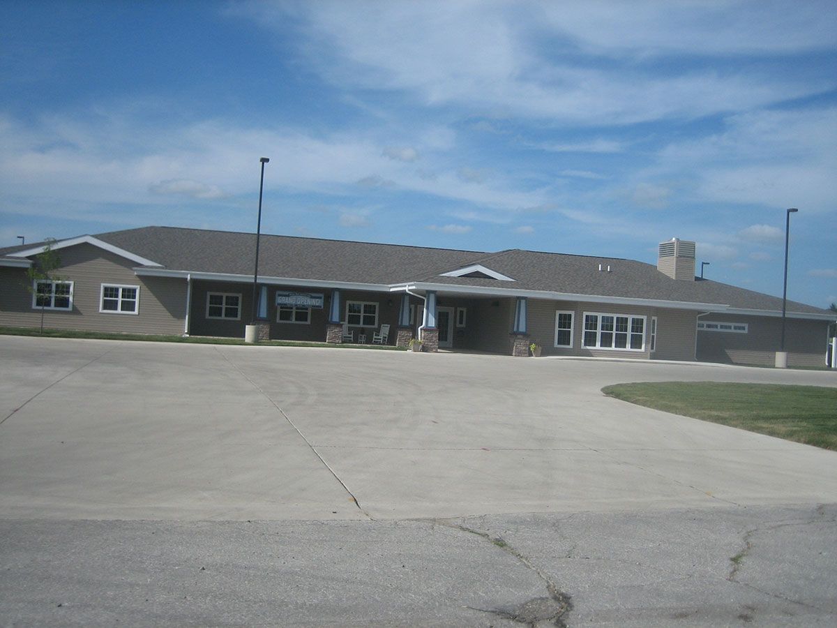A single-story school building with a parking lot in front, under a partly cloudy sky.