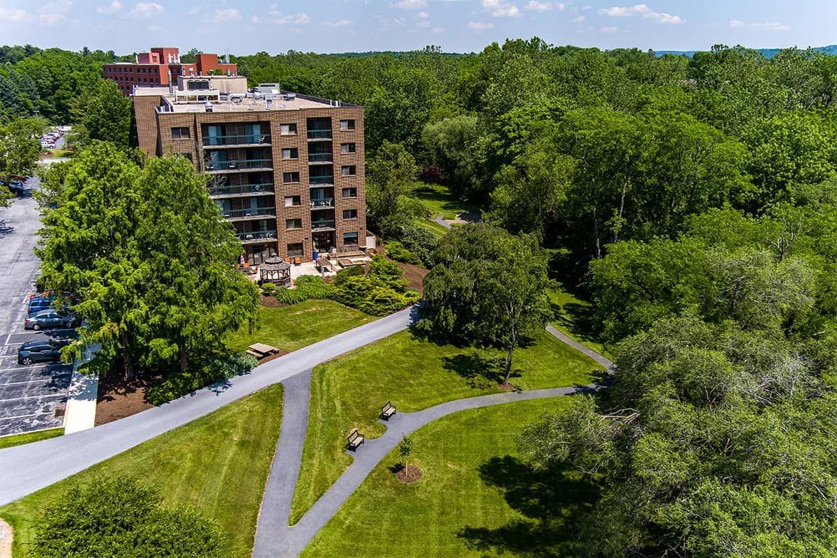 Aerial view of an apartment building surrounded by lush greenery and winding pathways.