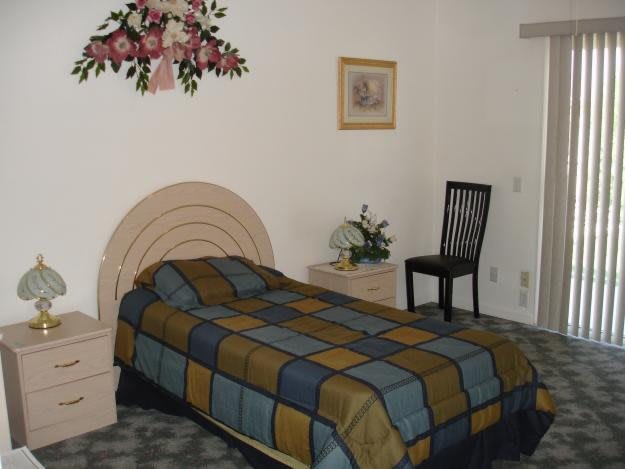 A cozy bedroom with a single bed, simple decor, and floral wall decorations.
