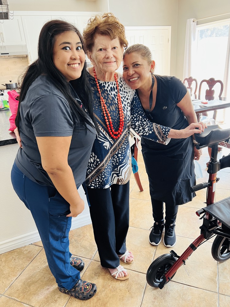 Three people smiling indoors, posing with a walking aid.