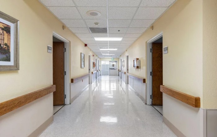 A clean and well-lit hospital corridor with multiple doors.