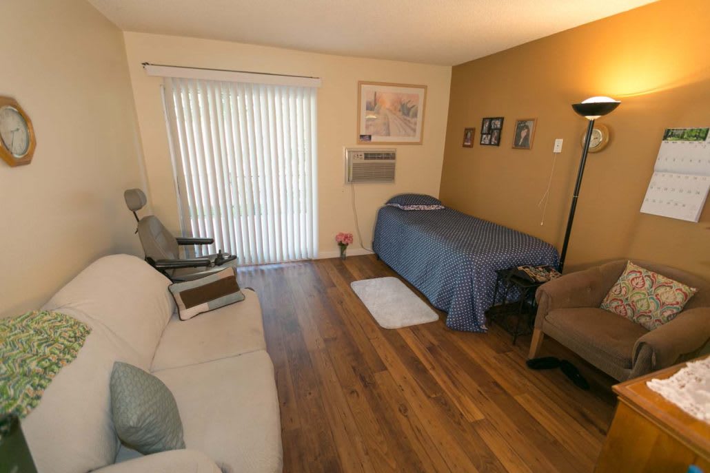 A cozy bedroom with a single bed, a comfortable couch, and warm wooden flooring.