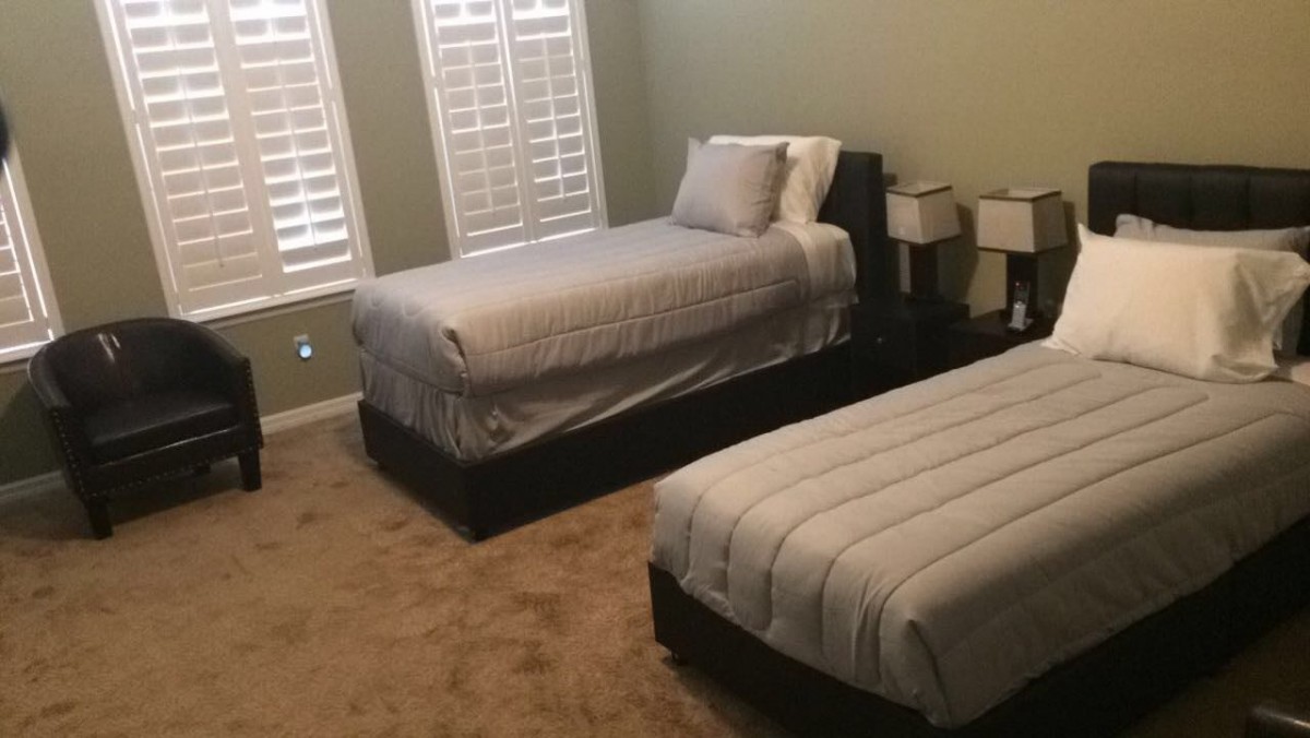 A tidy bedroom with two twin beds, neutral bedding, and side lamps.