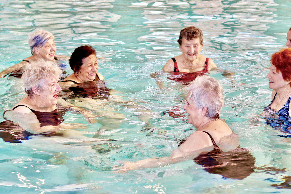A group of elderly women enjoying a water exercise session in a swimming pool.