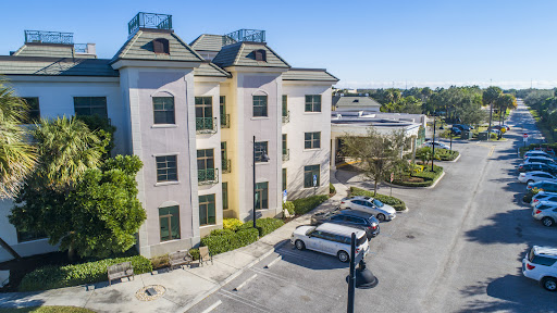 A modern three-story residential building with parking and clear blue skies.