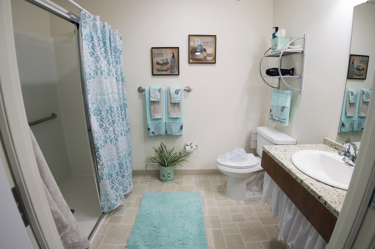 A well-decorated bathroom with a shower curtain, towels, and a bath mat in matching pastel colors.