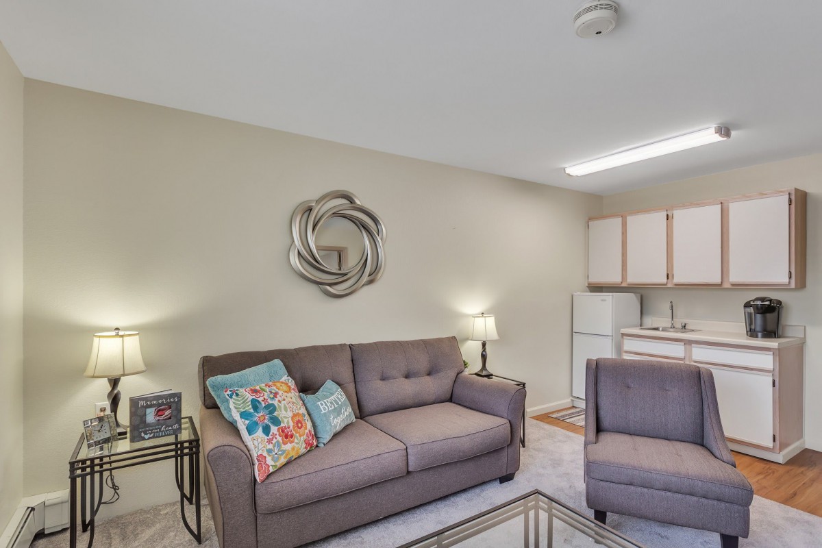 A cozy living room with a modern sofa and colorful cushions, accented by minimalist wall art and warm lighting.
