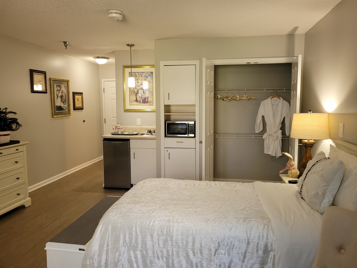 A cozy hotel room with a bed, closet, and amenities like a microwave.