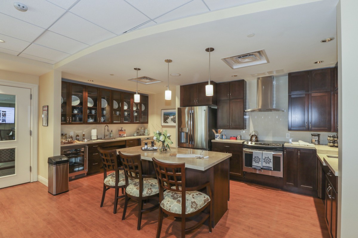 A modern kitchen featuring an island with bar stools, pendant lighting, and stainless steel appliances.