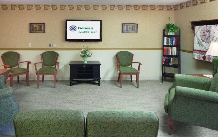 A waiting room with chairs, a television, and a bookshelf.