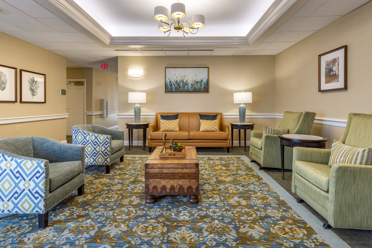 A cozy living room with comfortable sofas, armchairs, and a central coffee table surrounded by lamps.