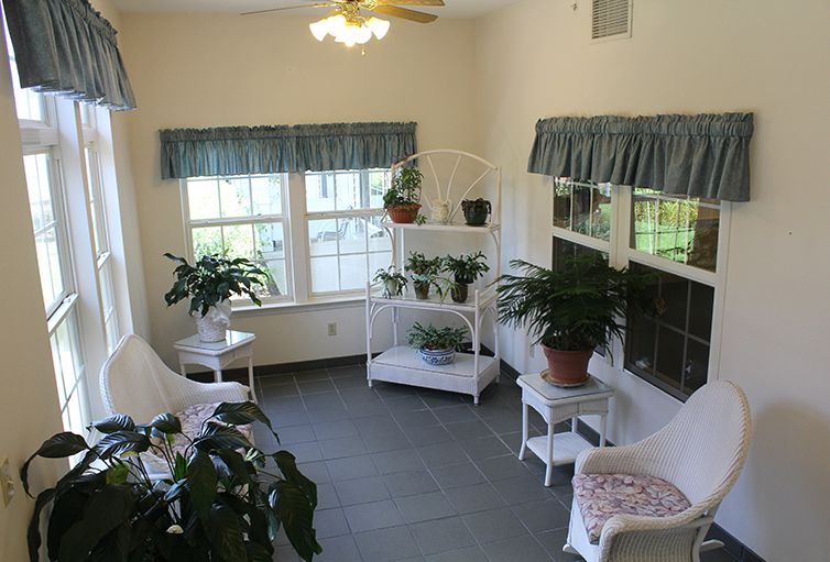 A cozy sunroom filled with wicker furniture and vibrant indoor plants.