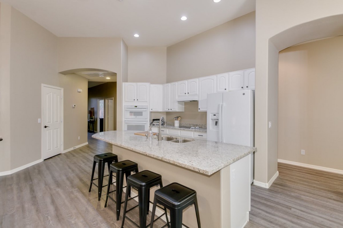 A modern kitchen featuring a central island with stools, white cabinetry, and recessed lighting.