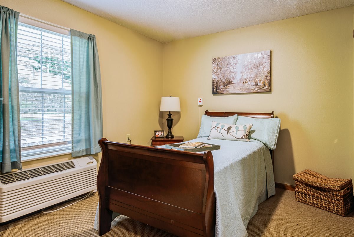 Cozy bedroom with a wooden bed, lamp, and decorative painting.
