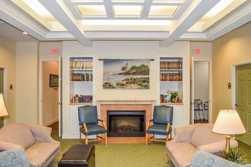 A cozy living room featuring a fireplace, chairs, sofas, bookshelves, and a painting on the wall.