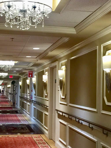 A luxurious hotel hallway featuring elegant lighting and patterned carpet.