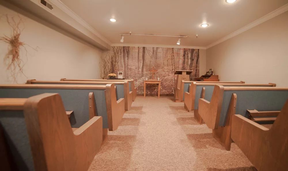A small chapel interior with bench seating and a pulpit at the front.