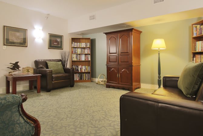 A cozy living room with a wooden cabinet, bookshelves, and comfortable seating.