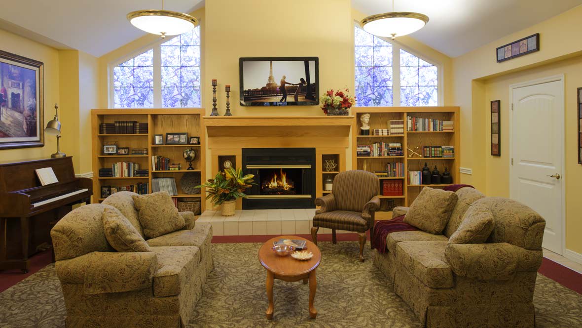 A cozy living room featuring a fireplace, sofas, and built-in bookshelves.