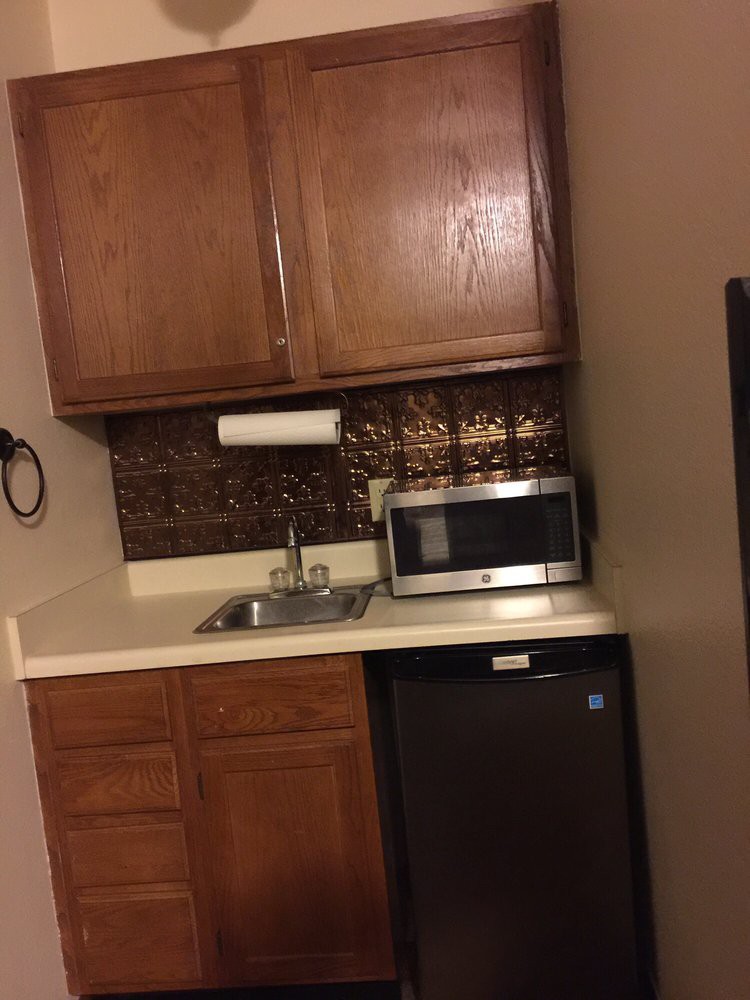 A small kitchen area with a microwave, sink, and mini fridge.