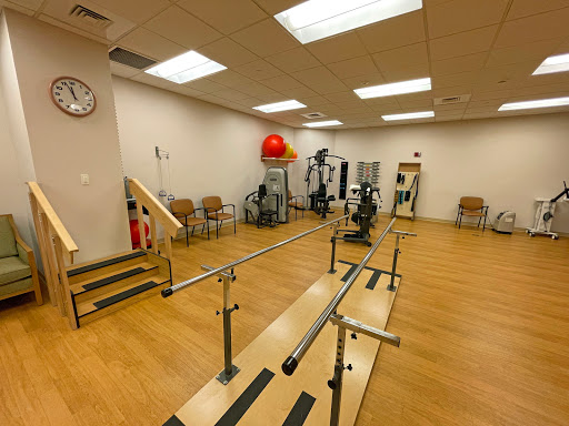 A physical therapy room equipped with exercise apparatus including parallel bars and fitness machines.