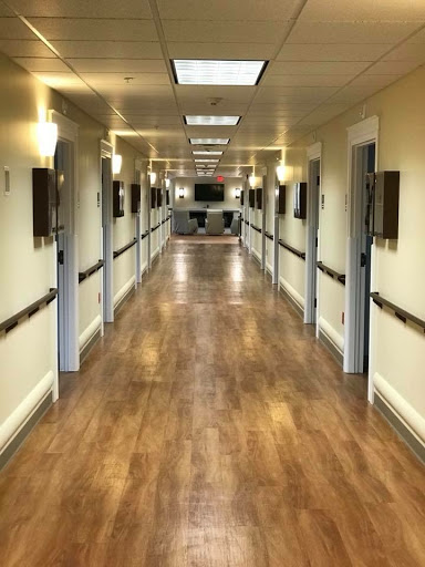 A well-lit corridor with doors on either side, featuring wooden flooring and a clean, organized appearance.