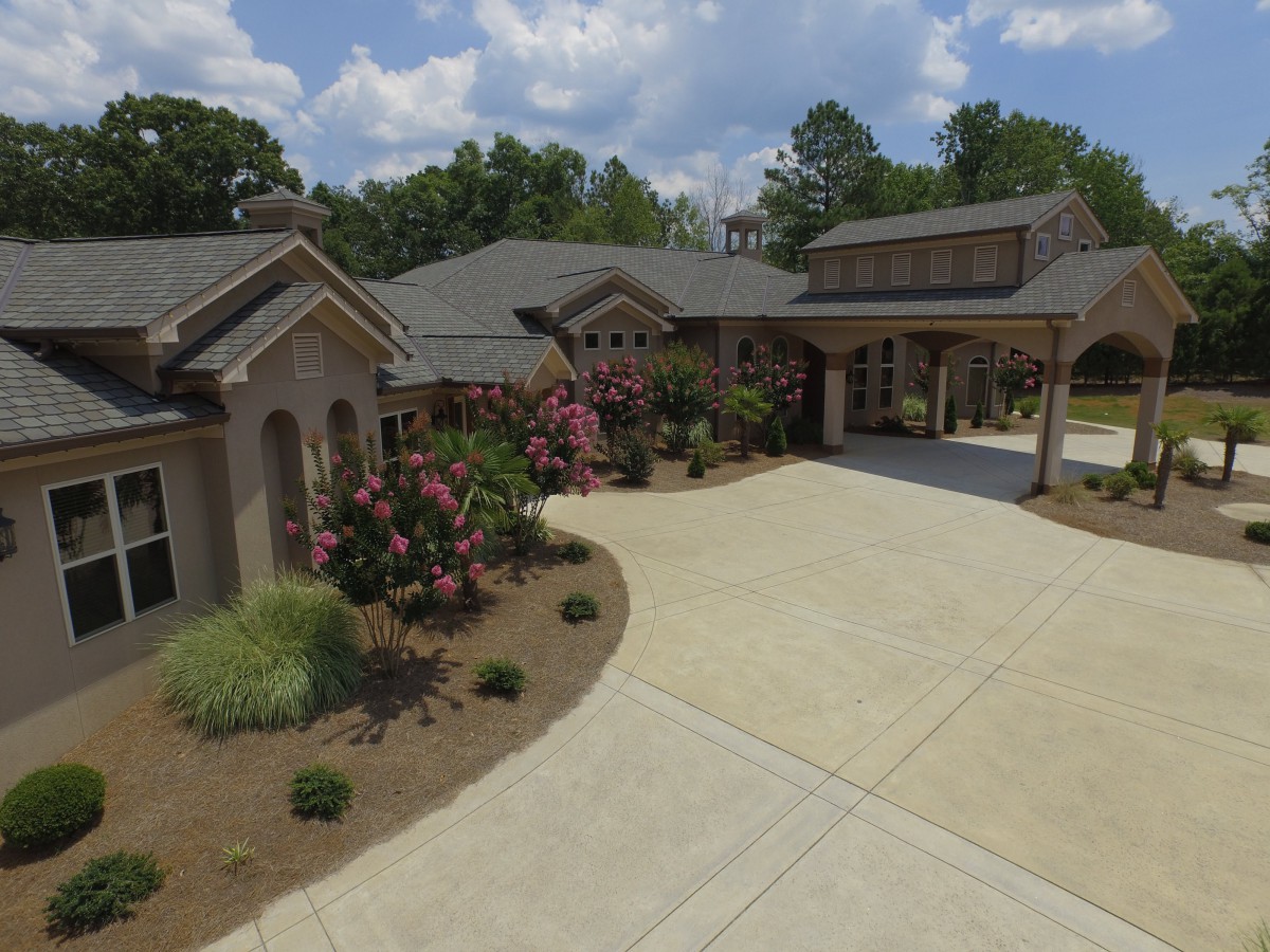 A spacious residential house with a driveway and well-maintained landscaping on a sunny day.