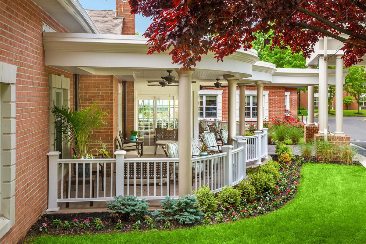 A charming house with a spacious porch overlooking a well-maintained garden.
