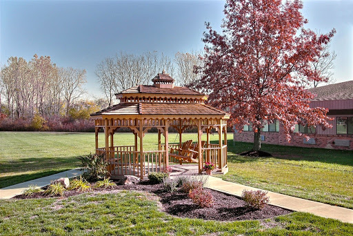 A beautiful wooden gazebo surrounded by lush greenery and blooming trees, perfect for enjoying the outdoors.
