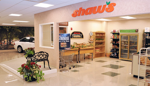 Entrance to Shaw's grocery store featuring fresh produce and shopping carts.