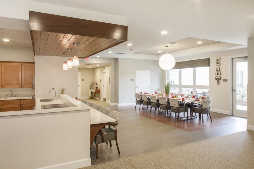 A modern dining room with a large table set for a meal and an adjacent kitchen area.