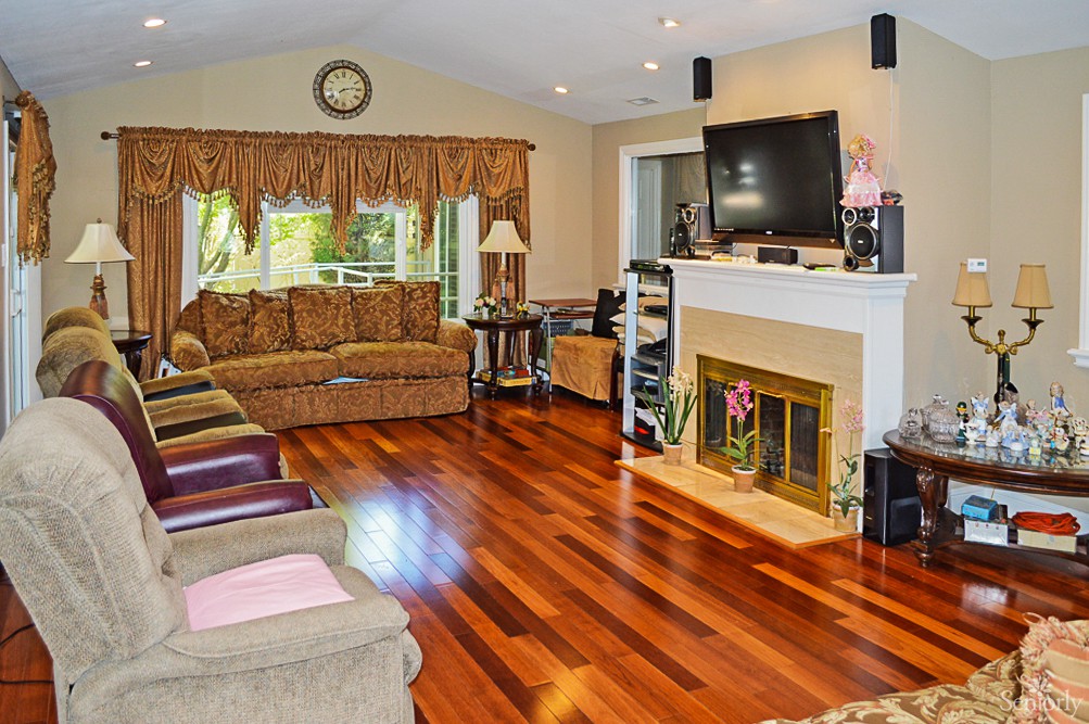 A cozy living room with hardwood floors, a fireplace, and a large TV.