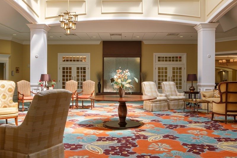 A stylish hotel lobby featuring elegant furniture and a colorful carpet.