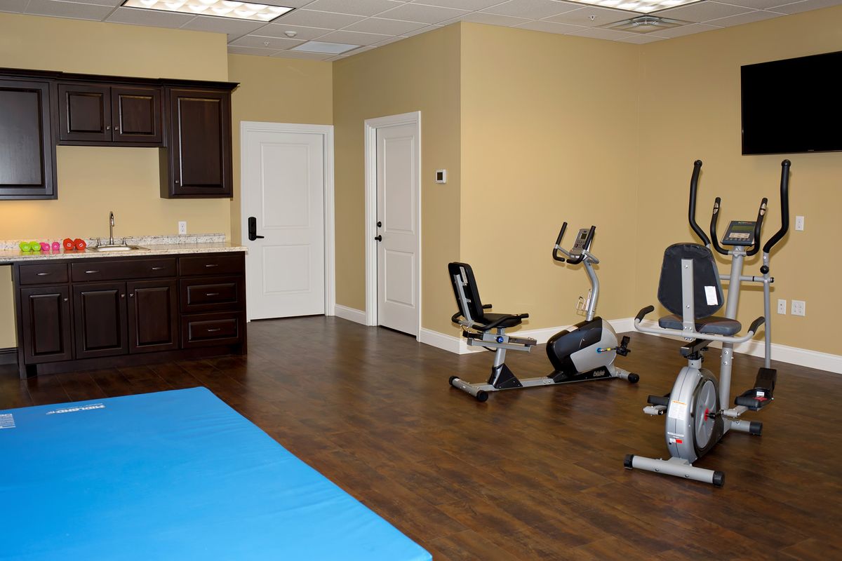 A compact home gym featuring a stationary bike and exercise mat in a small room.