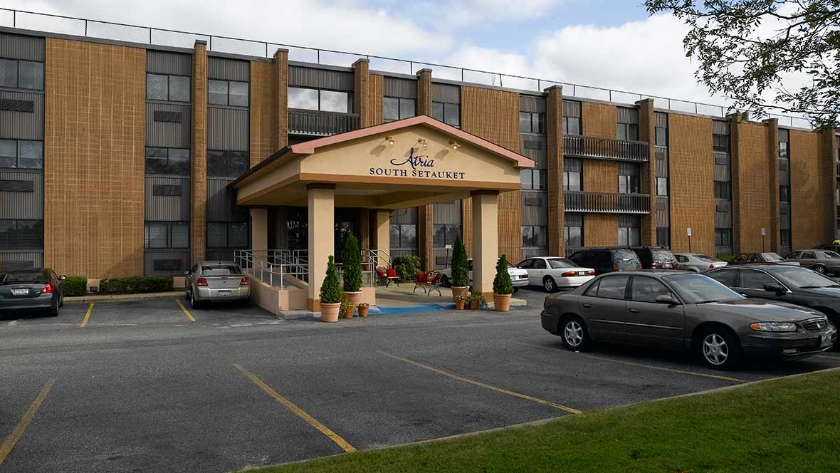 A hotel entrance with a parking area in front.