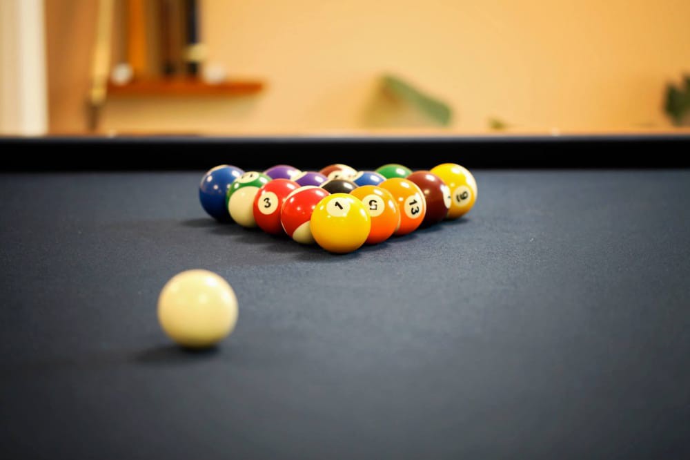 A set of billiard balls racked up on a pool table, ready for the break.