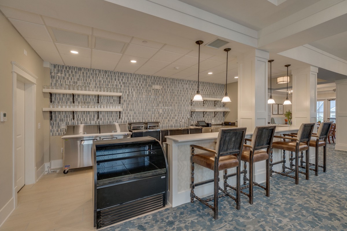 A modern kitchen area with a sleek countertop, bar stools, and stylish pendant lighting.
