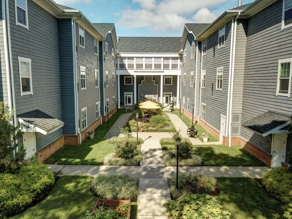 A view of a well-maintained apartment complex courtyard featuring green landscaping and outdoor seating.
