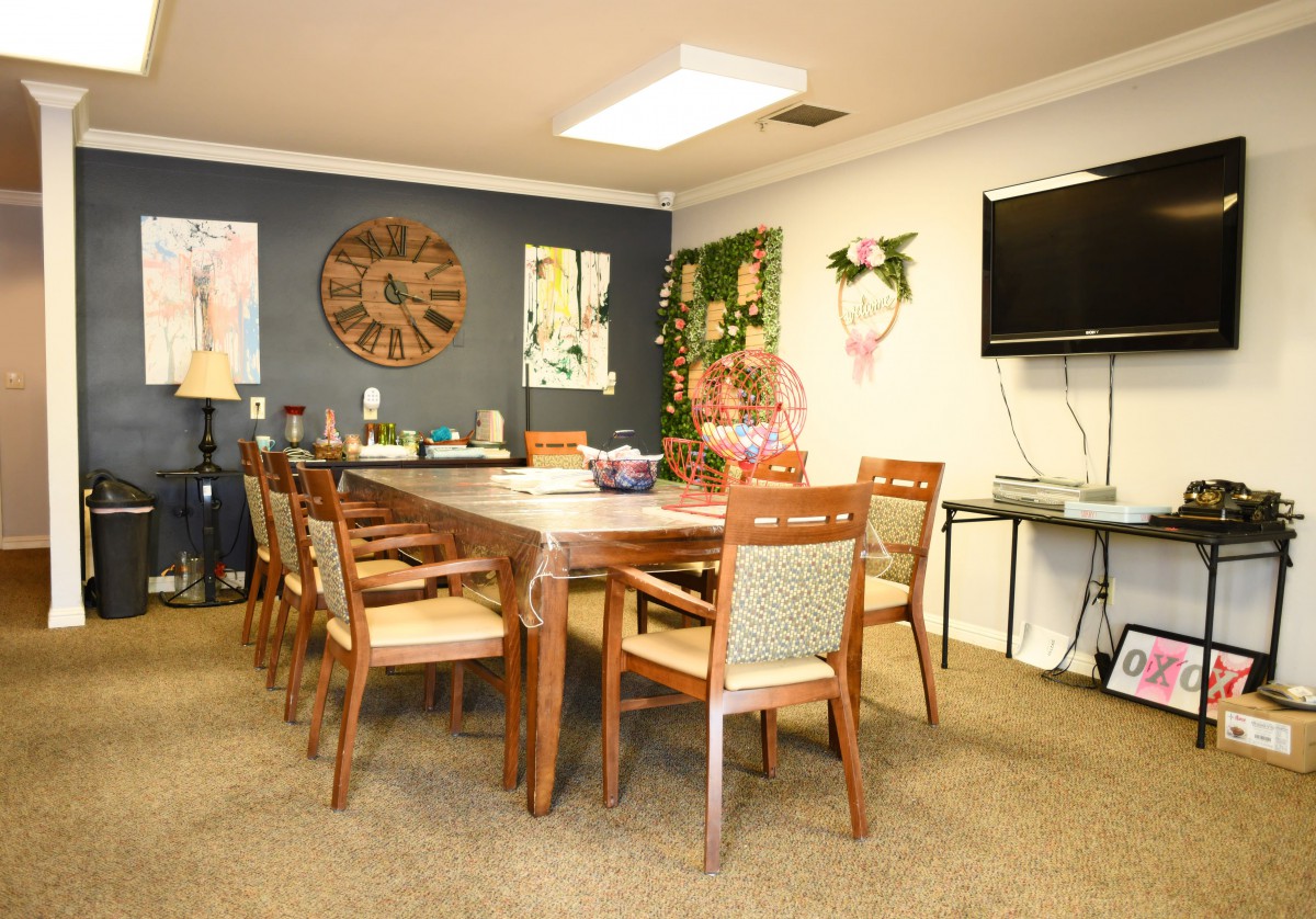 A conference room with a large wooden meeting table surrounded by chairs, adorned with wall art and decorations.