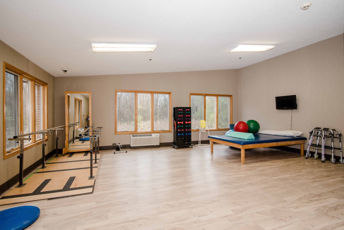 A spacious rehabilitation room equipped with therapy tools and exercise balls.