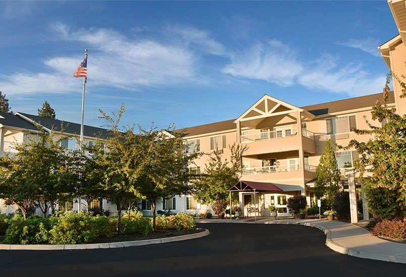 A multi-story residential building with a driveway and flagpole in front.
