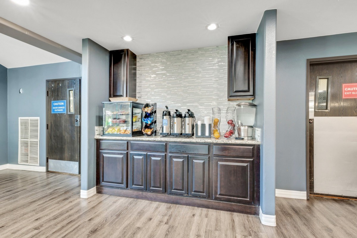 A modern beverage station with coffee dispensers, cabinets, and snacks in a stylish interior.