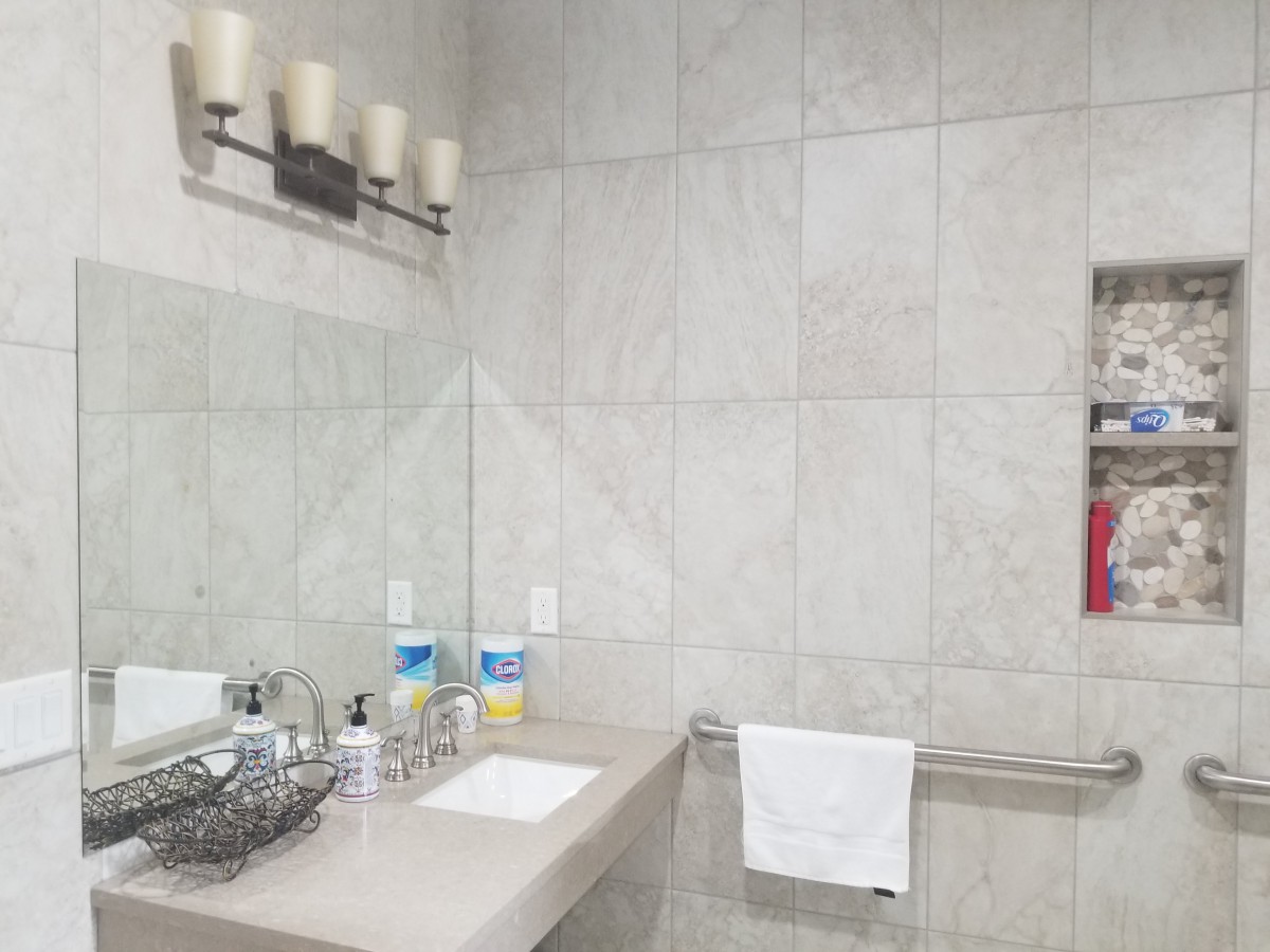 A clean and modern bathroom with a sink, mirror, and toiletries.