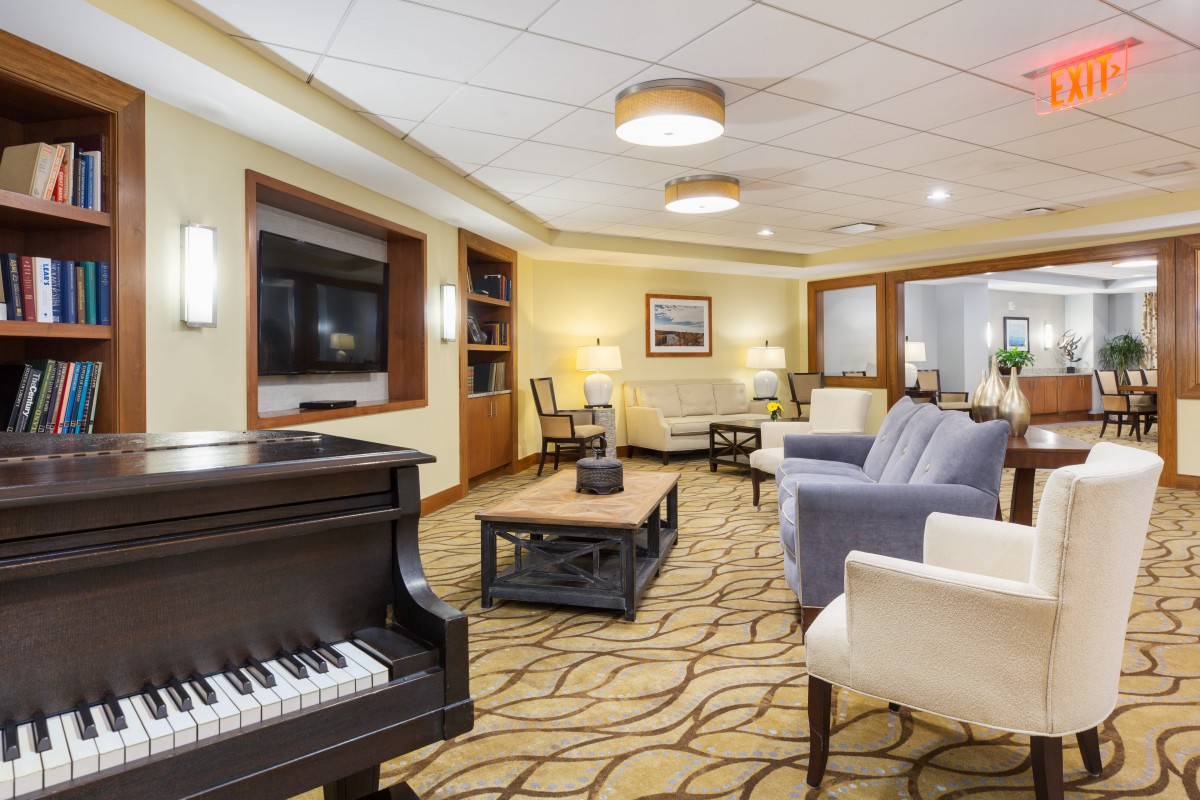 A cozy lounge area featuring a piano, comfortable seating, and a television.