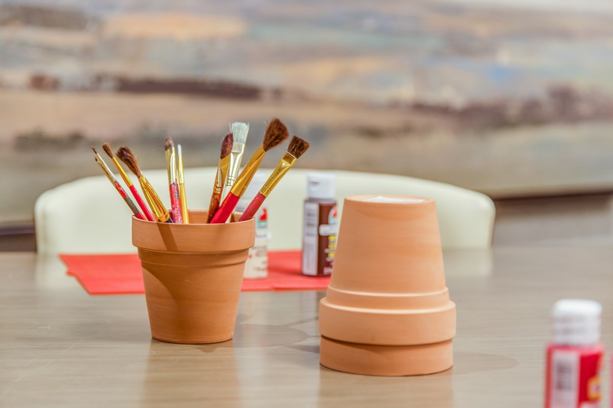 Art supplies including paintbrushes and clay pots set up for a crafting session.