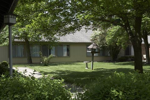 A suburban house surrounded by trees and a well-maintained yard.