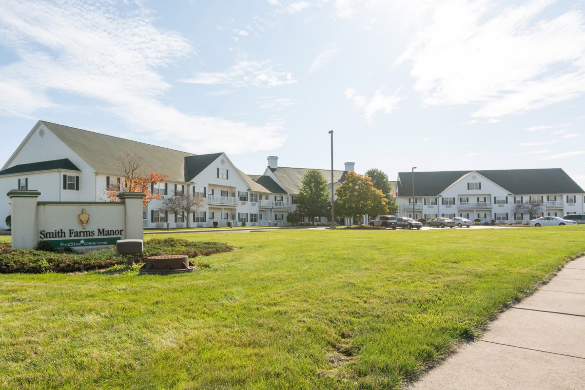 A large residential building with a well-maintained lawn under a partly cloudy sky.