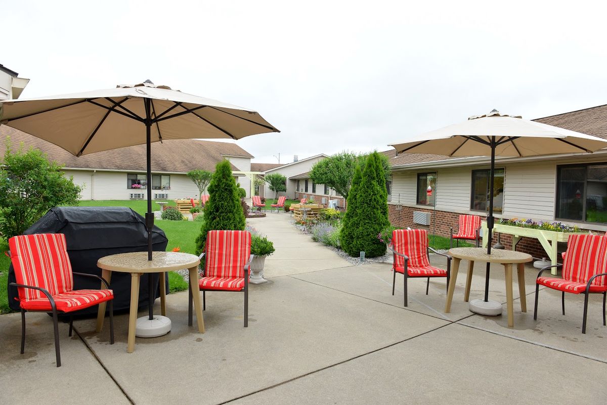 A well-maintained patio area with tables, chairs, and umbrellas set amidst beautiful landscaping.