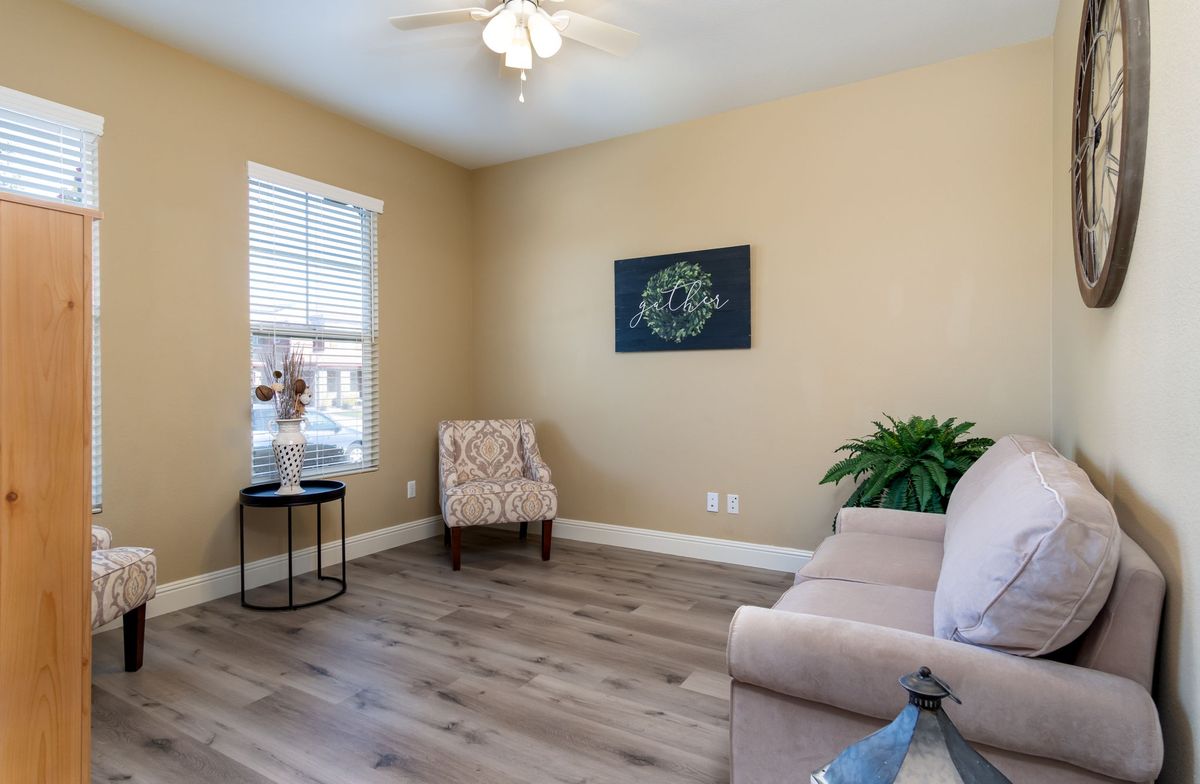 A minimalist living room with a beige sofa, an accent chair, and wall art.
